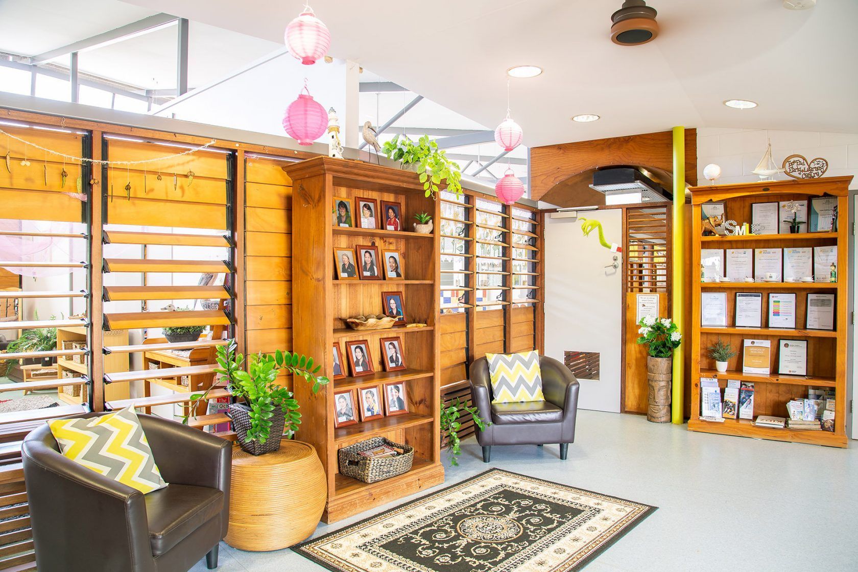 Cozy waiting room with wooden shelves, armchairs, and decorative items; bright and inviting.