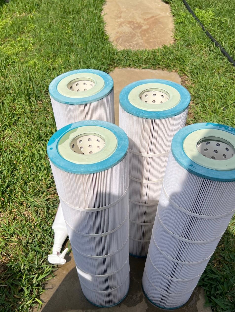 Four pool filters are stacked on top of each other on a concrete surface.