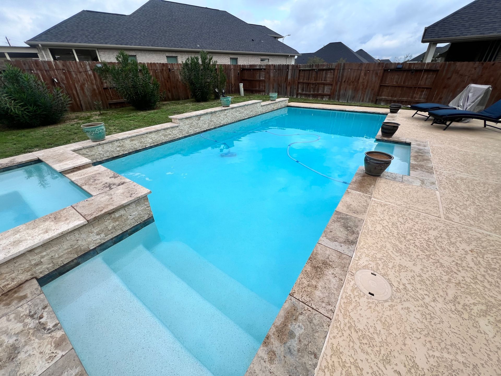 There is a large swimming pool in the backyard of a house.