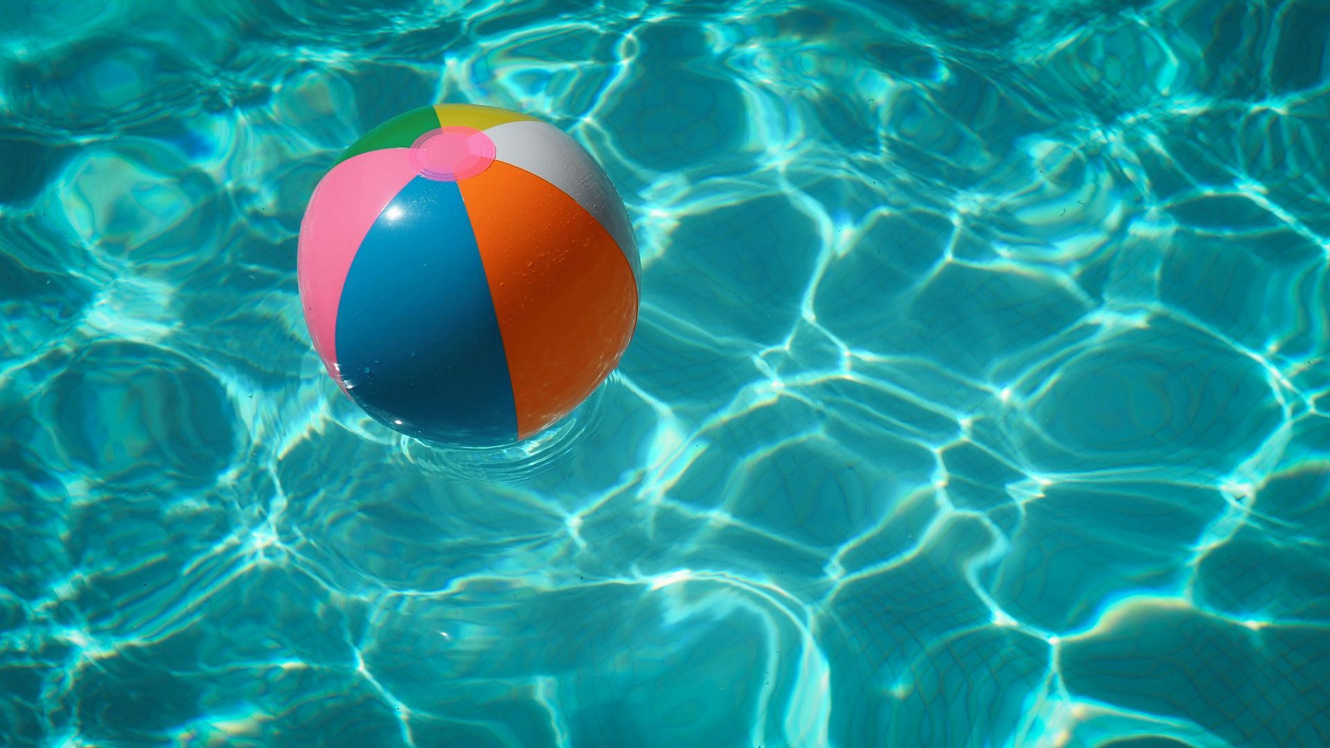 A colorful beach ball is floating in a swimming pool.