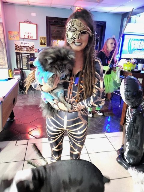 A woman in a mask is holding a small dog