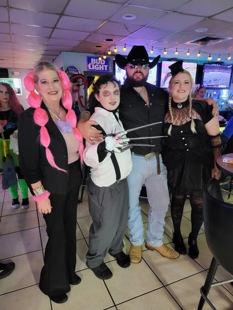A group of people posing for a picture in front of a bud light sign