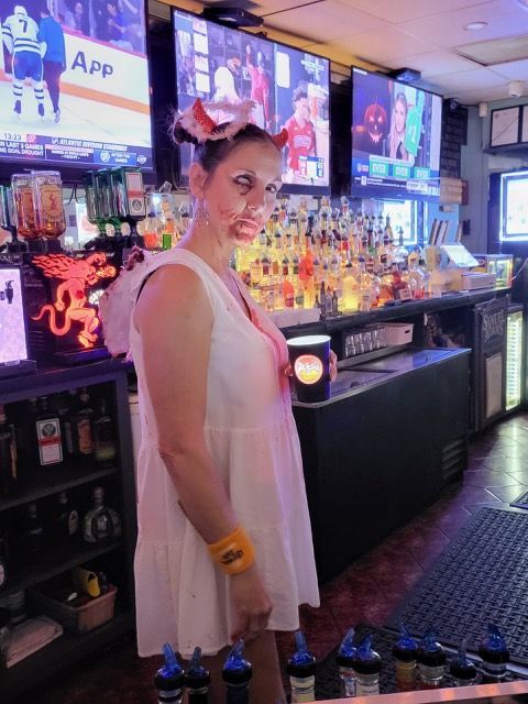 A woman in a pink dress is standing in front of a bar