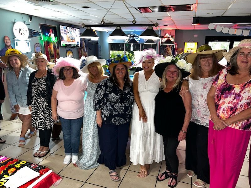 A group of women wearing hats are posing for a picture.