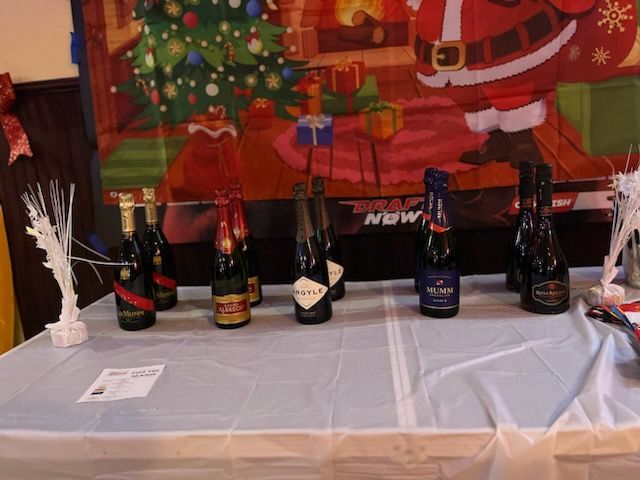 Several bottles of wine are on a table in front of a santa poster