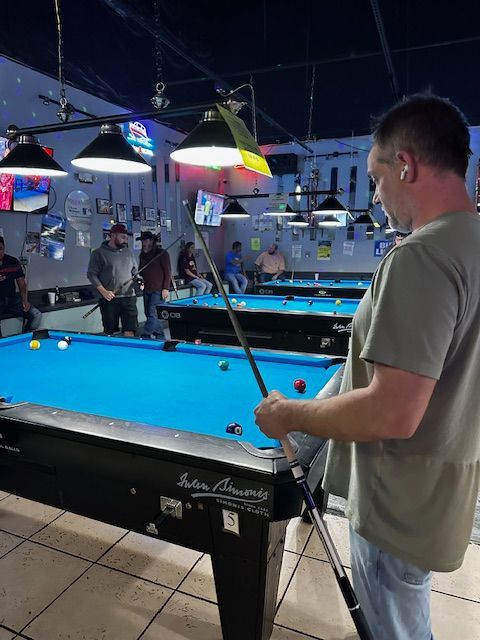 A man is playing pool in a pool hall