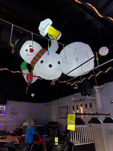 A large inflatable snowman is hanging from the ceiling of a restaurant.