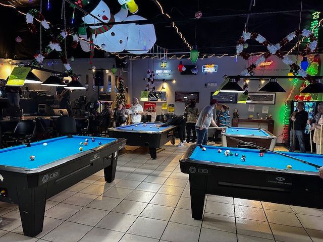 A pool hall filled with pool tables and people playing pool.