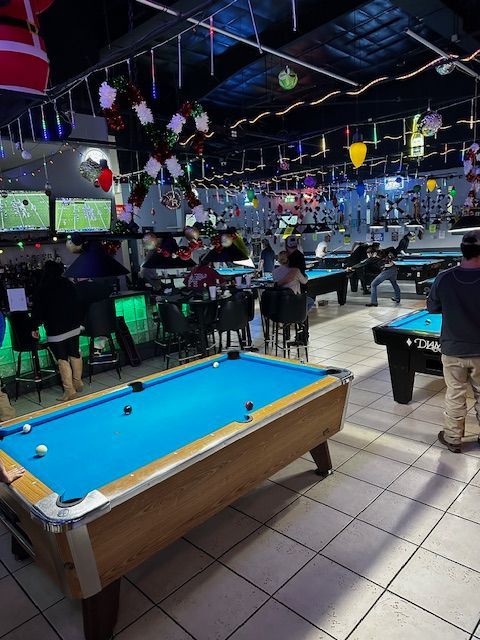 A pool table is in the middle of a pool hall