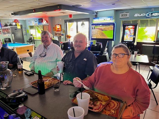 A group of people are sitting at a bar eating pizza and drinking beer.