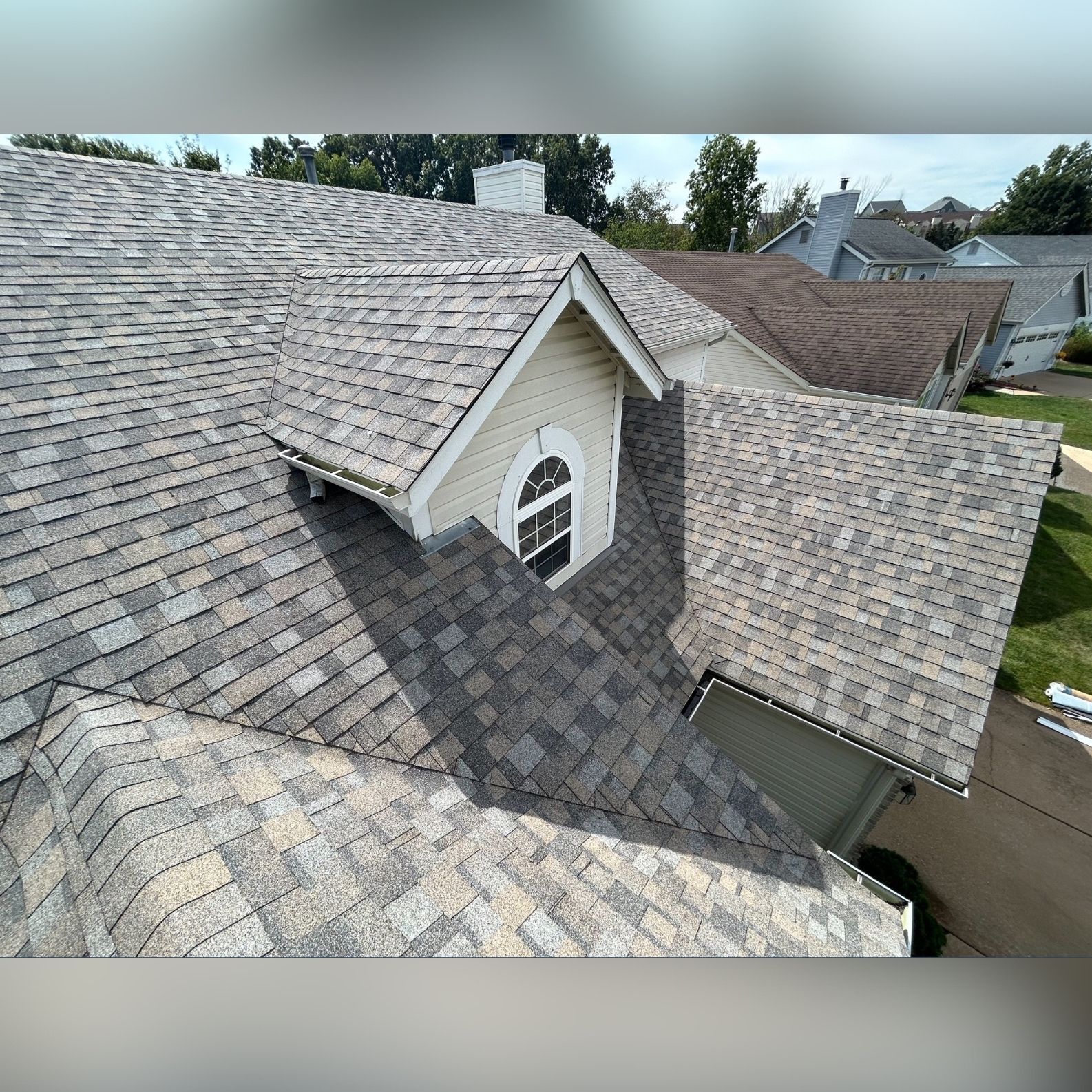 Close-up view of a multi-colored asphalt shingle roof with a dormer.