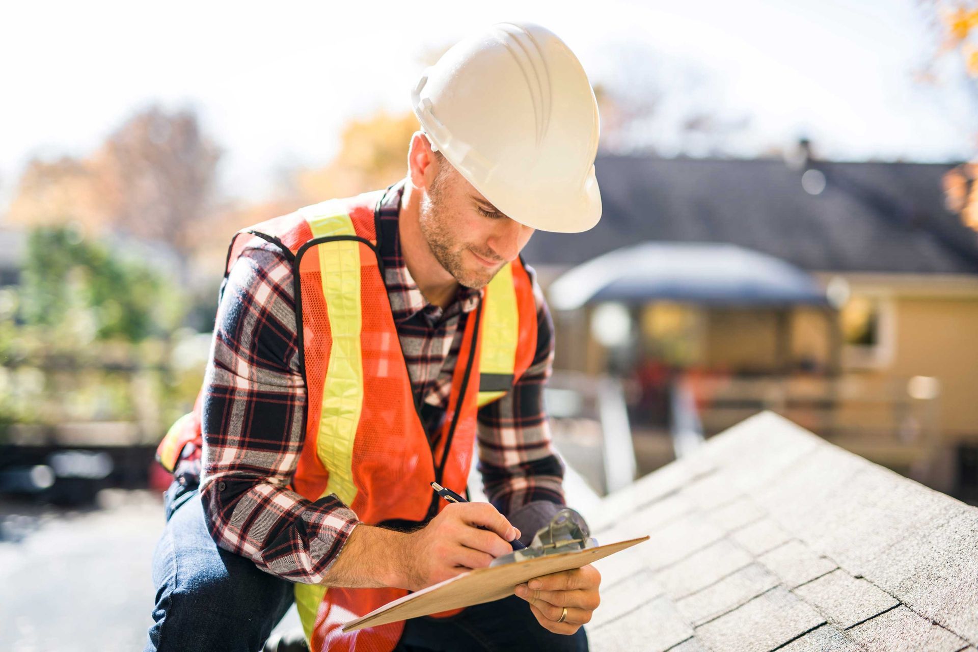 A man with a hard hat inspecting a house roof. A man with a hard hat inspecting a house roof.