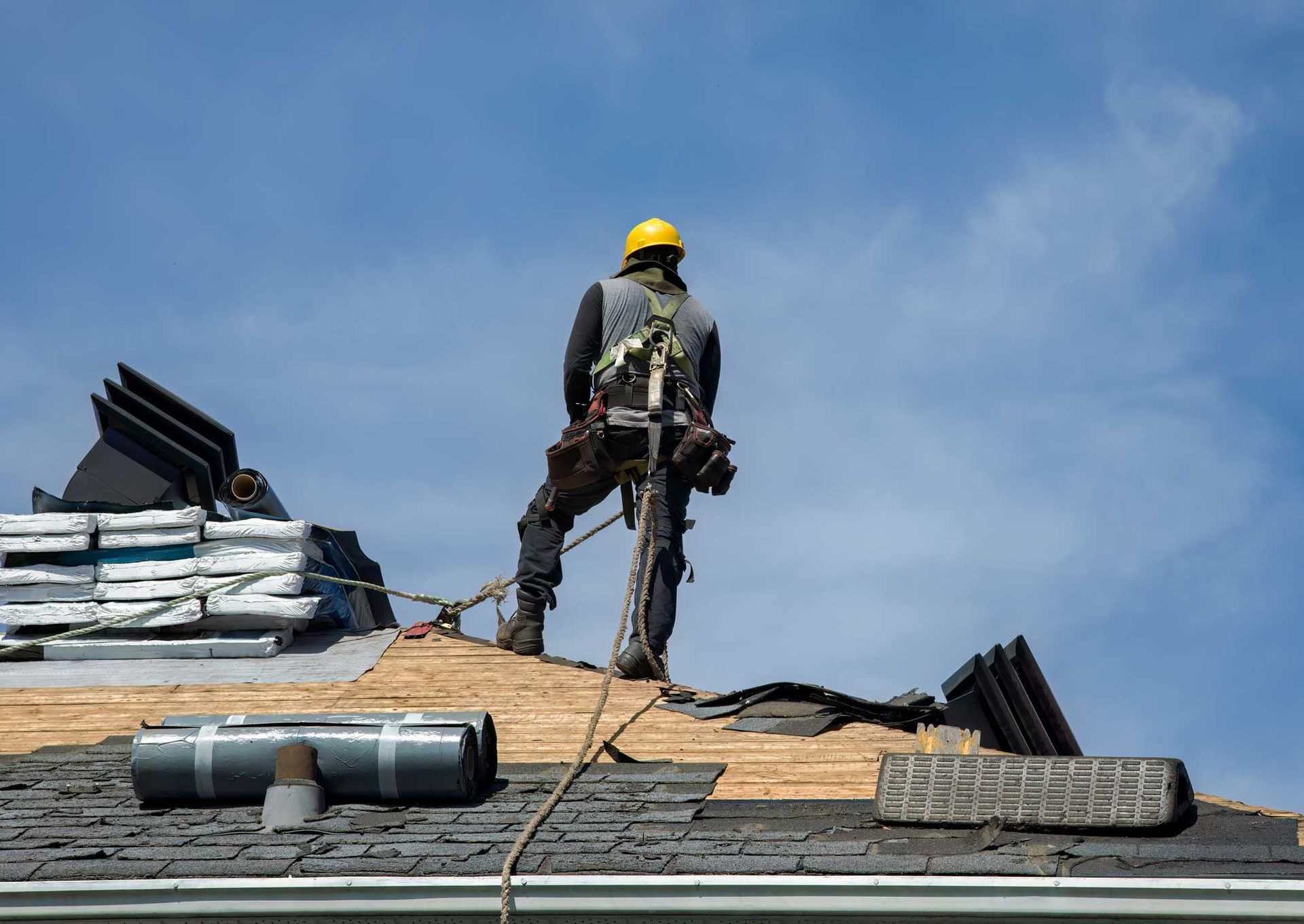 A professional roofer installing shingles on a residential roof. A professional roofer installing shingles on a residential roof.