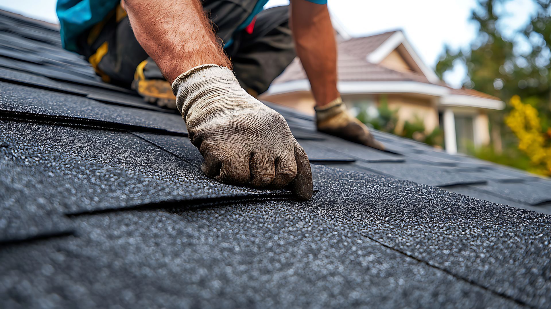 Professional roofing contractor installing new asphalt shingles on a residential home roof.