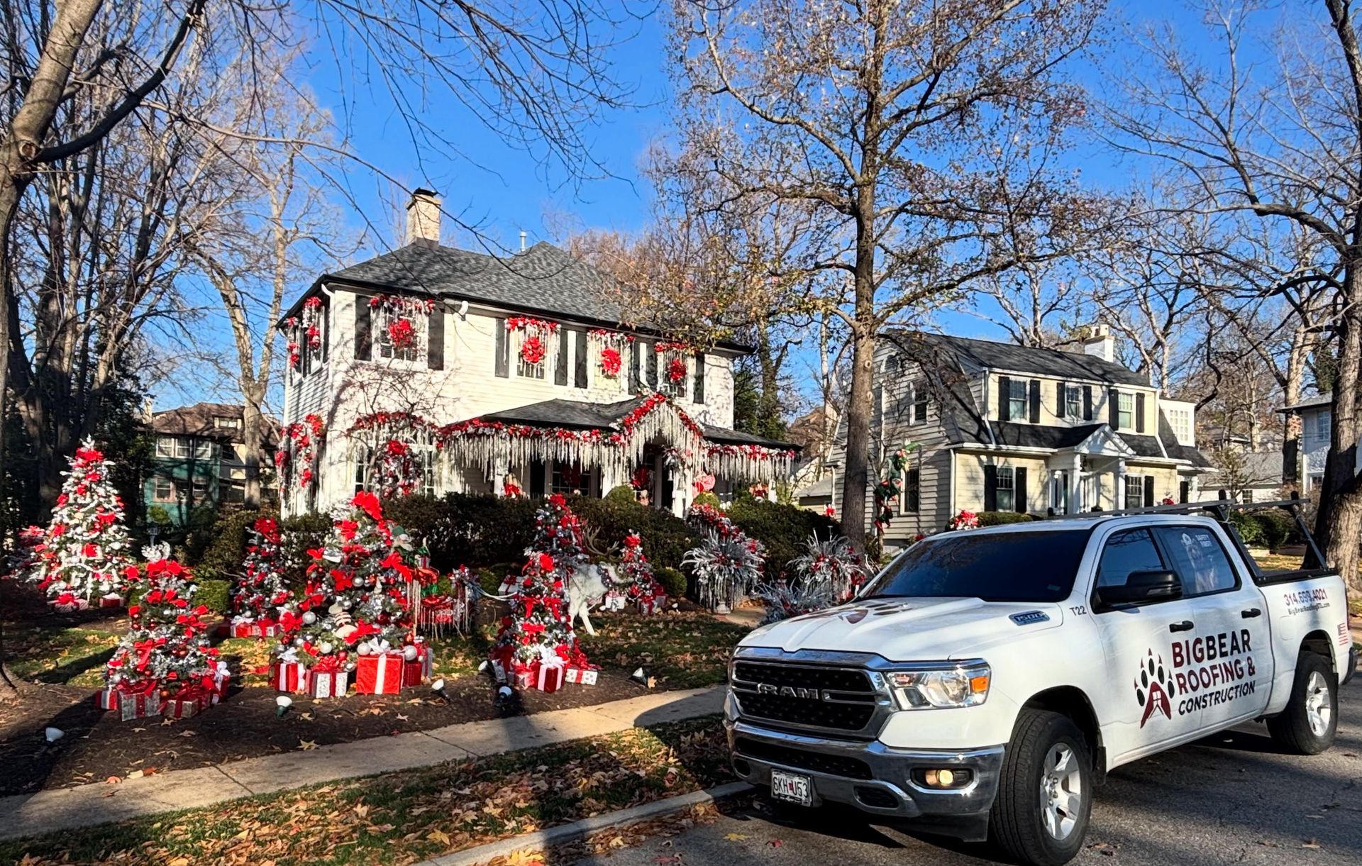 White truck parked in front of a house decorated with Christmas lights and wreaths.