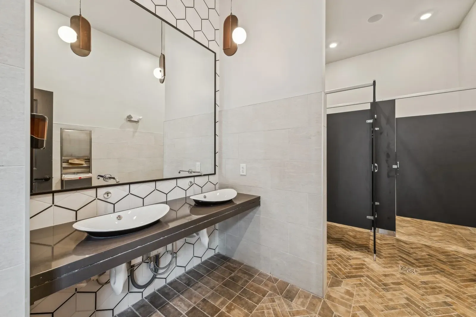 Two-sink bathroom vanity with large mirror and geometric tile backsplash.