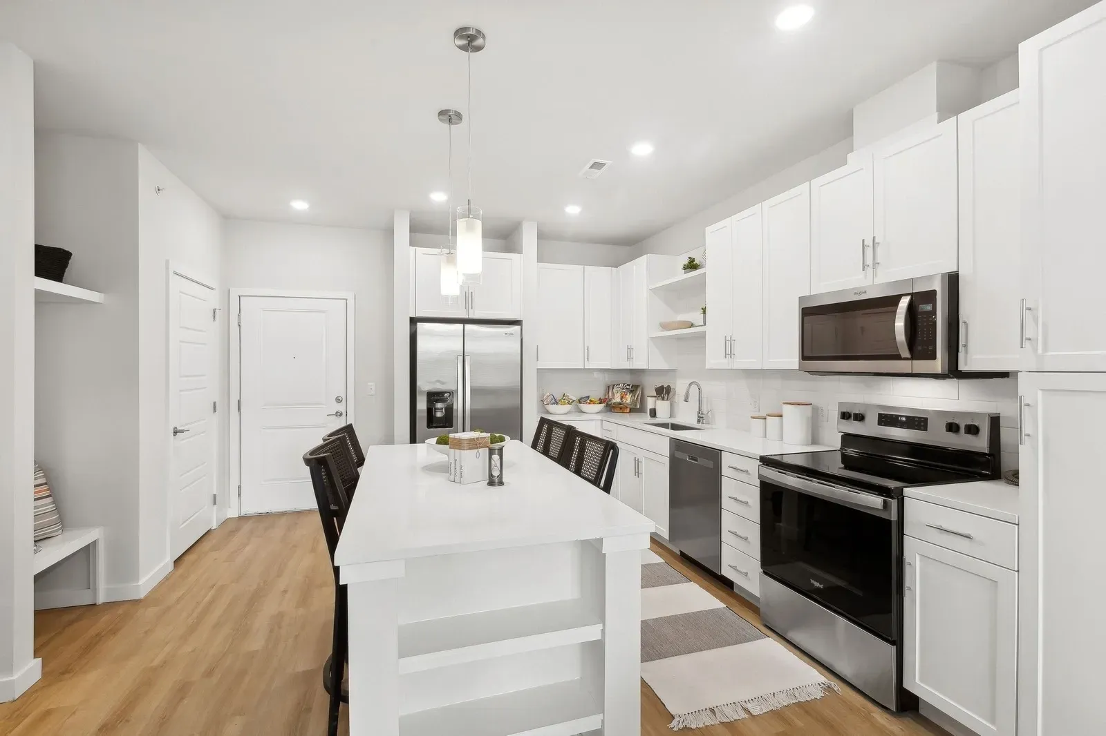 Bright white kitchen with an island and stainless-steel appliances.