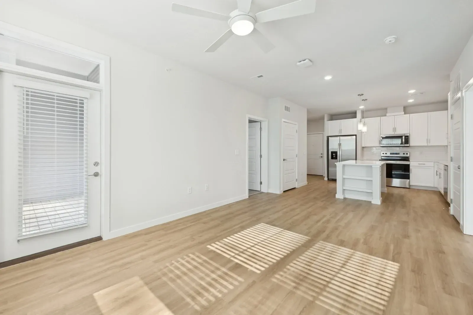 Open-concept living area with white kitchen, island, and stainless appliances.