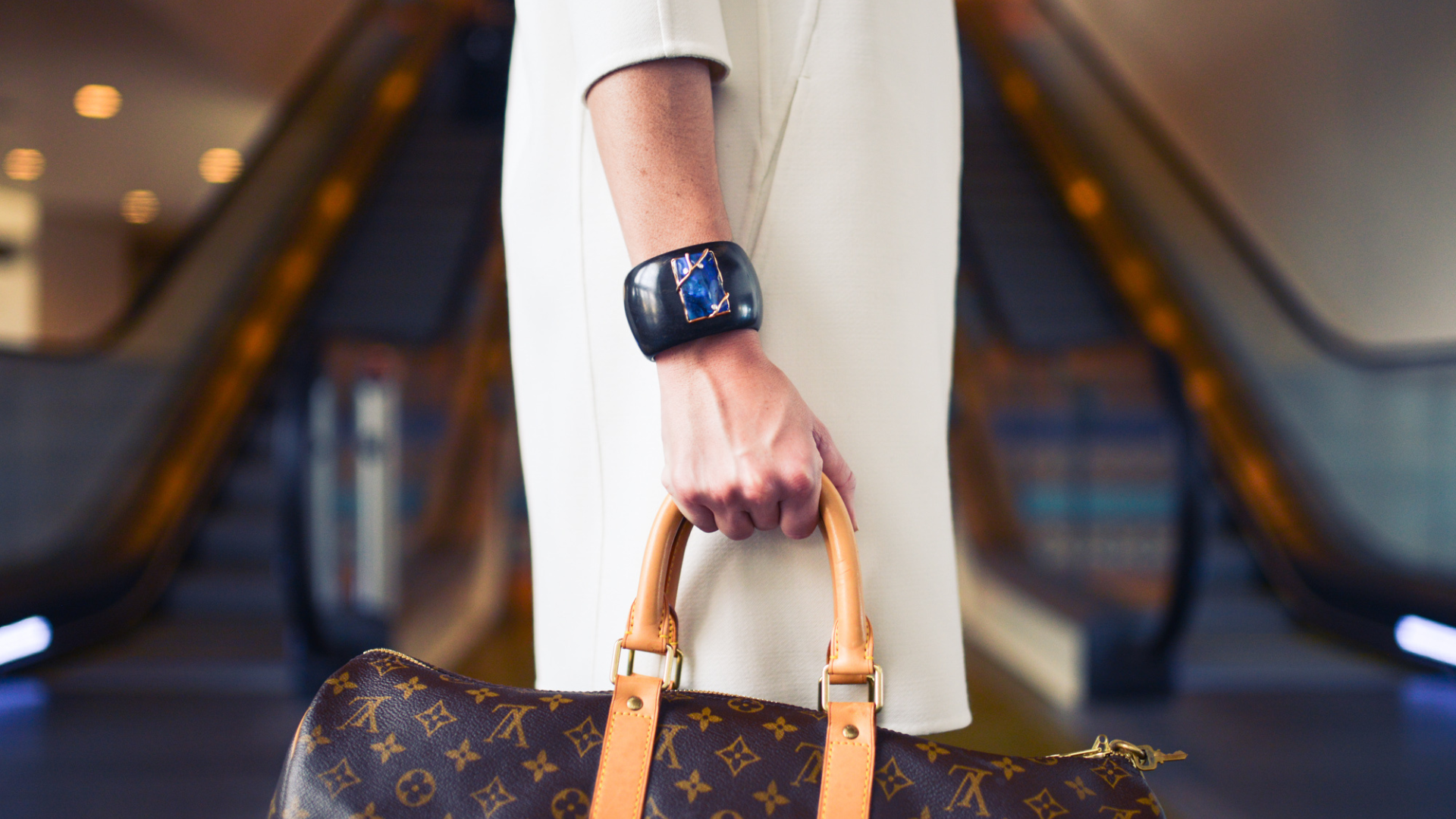 A woman in a white dress is holding a louis vuitton bag.