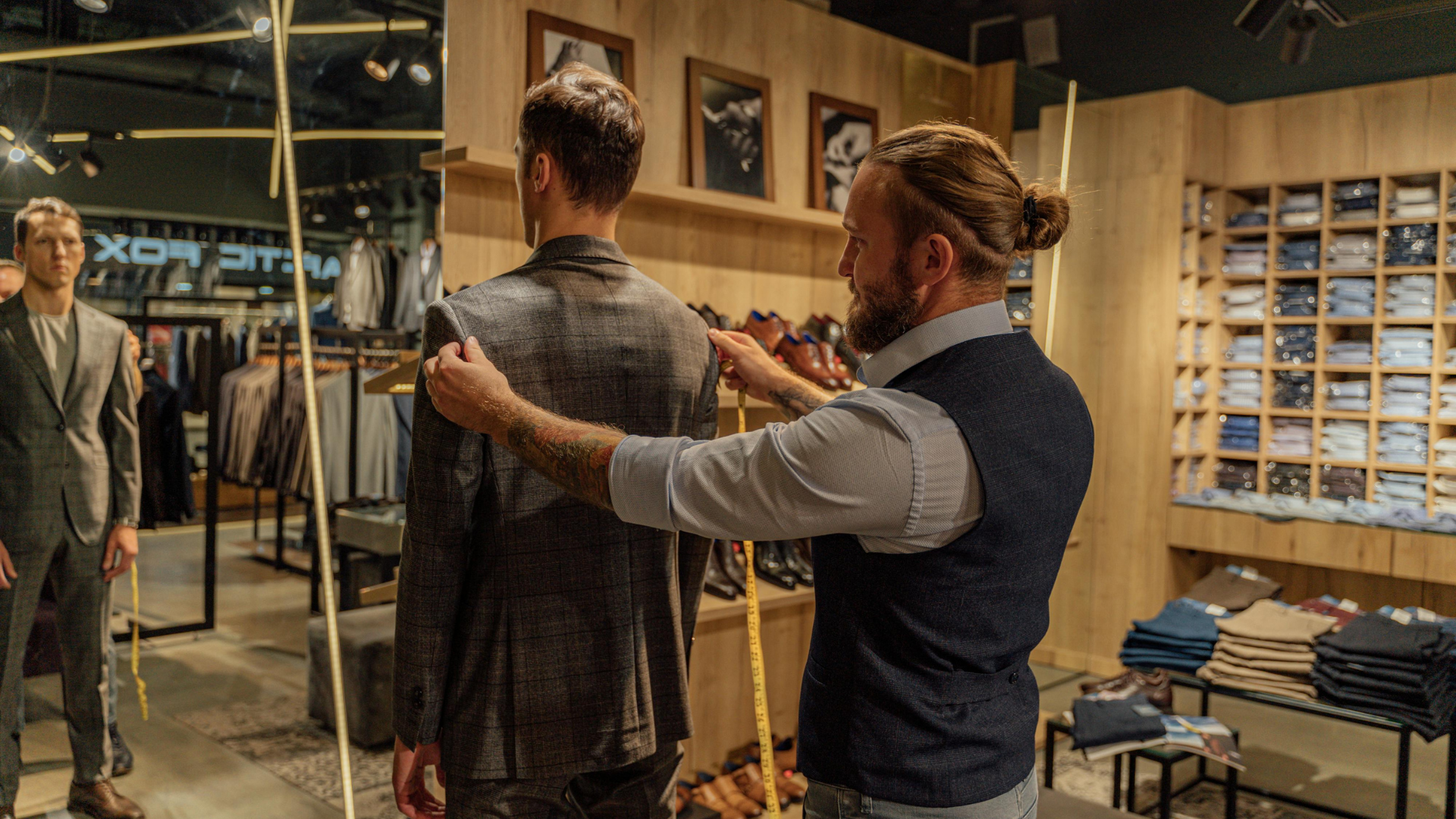 A man is getting his suit measured by a tailor in a store.