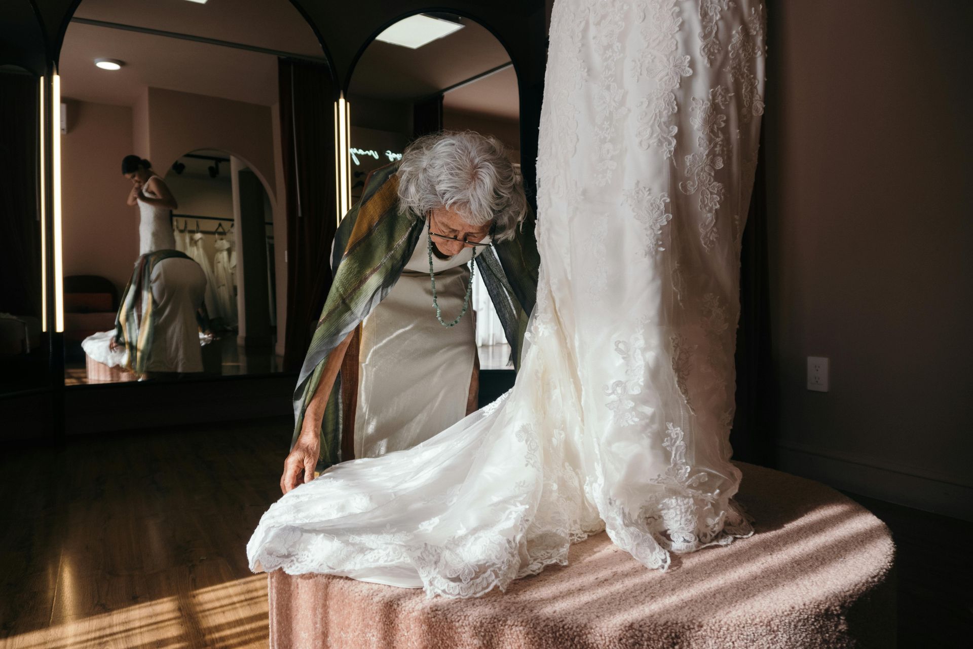 An elderly woman is trying on a wedding dress in a store.