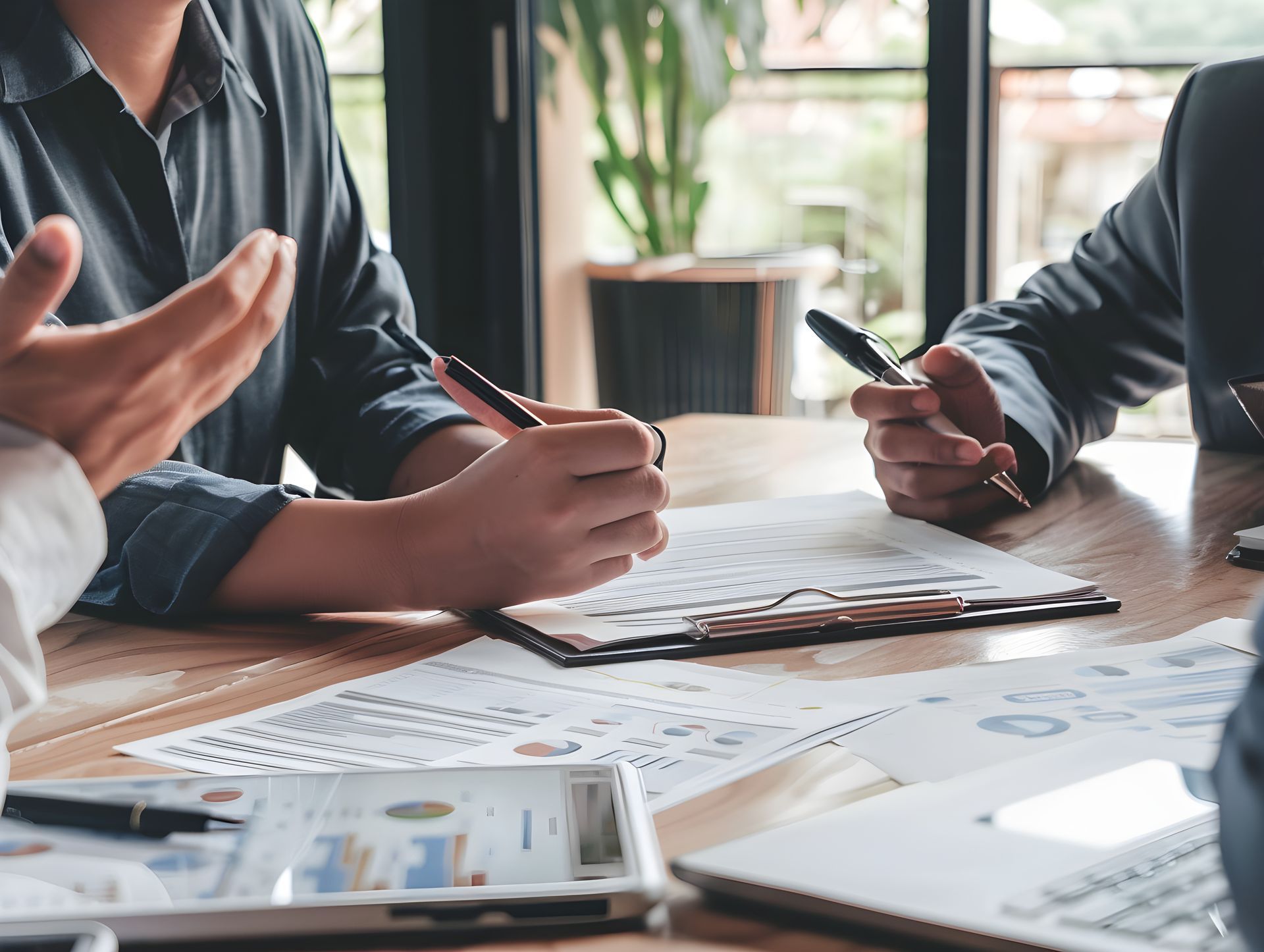 A group of people are sitting at a table with papers and pens.