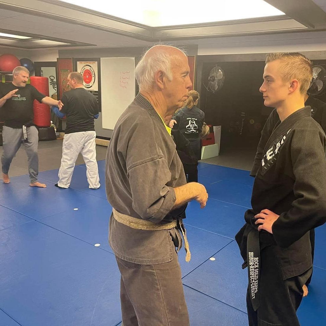 Brazilian Jiu Jitsu instructor in deep conversation with a student about techniques