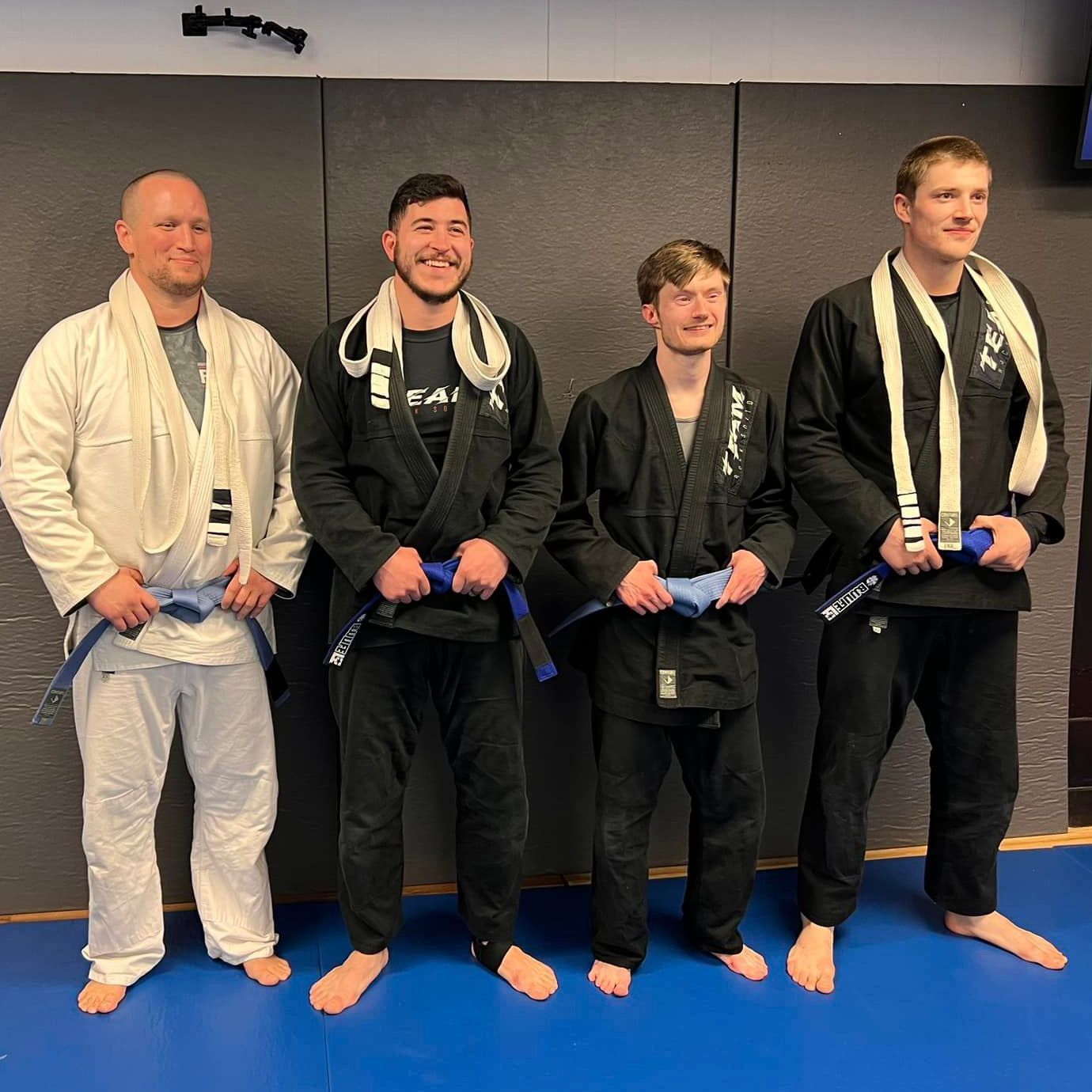 A group of men standing next to each other on a blue mat