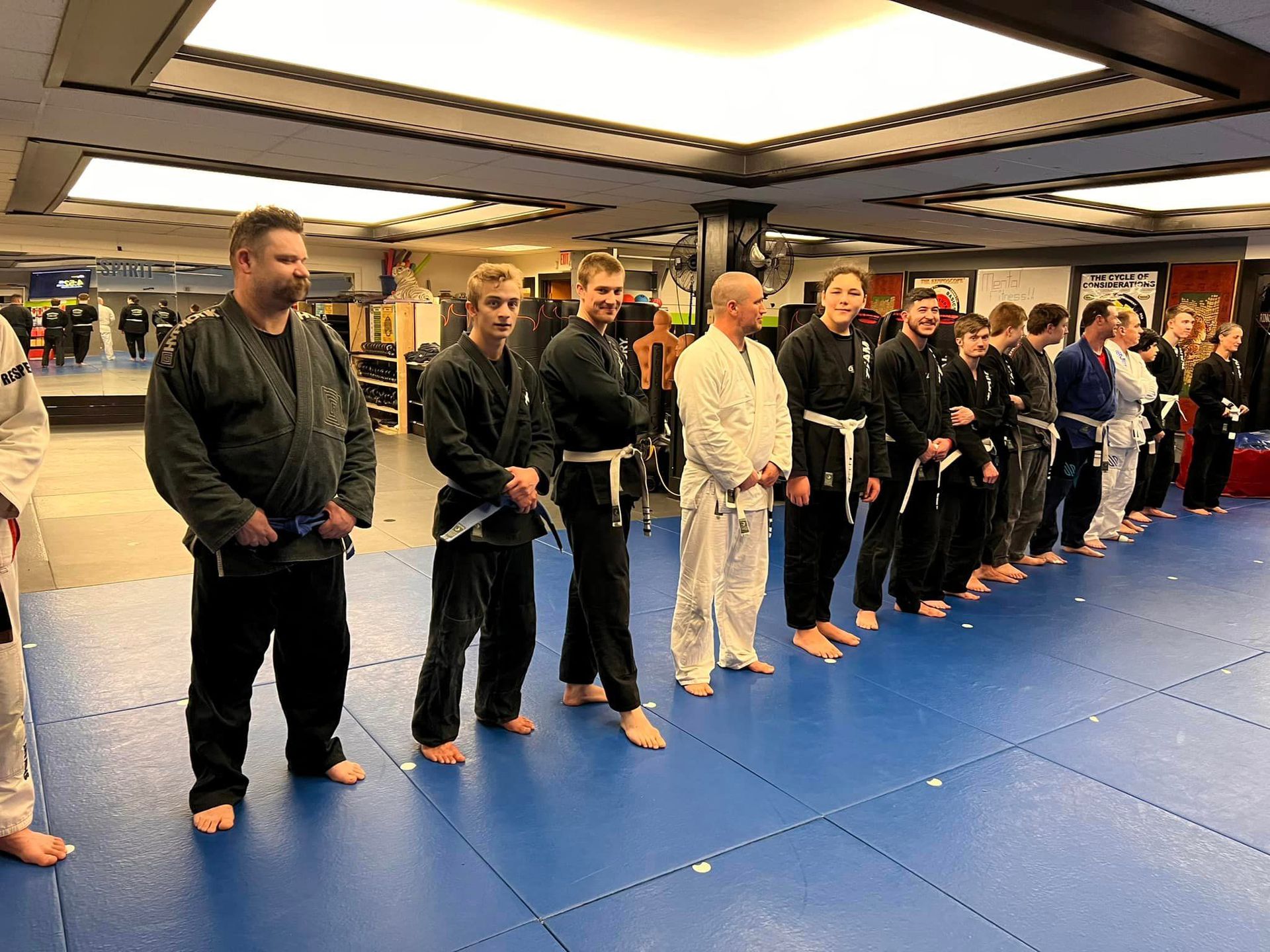 a team of MMA students lined up for a group photo in their training gear