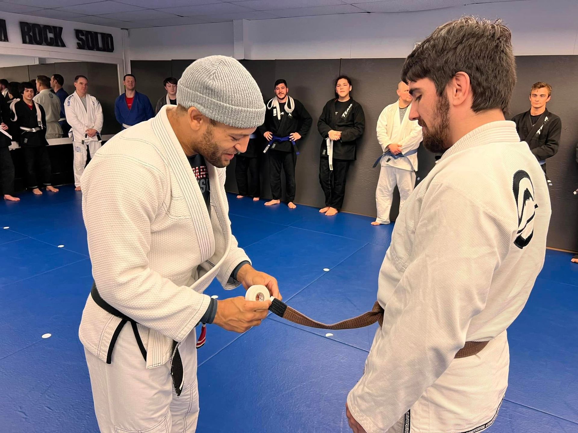 Mixed martial arts student proudly receiving a new belt as a sign of progress