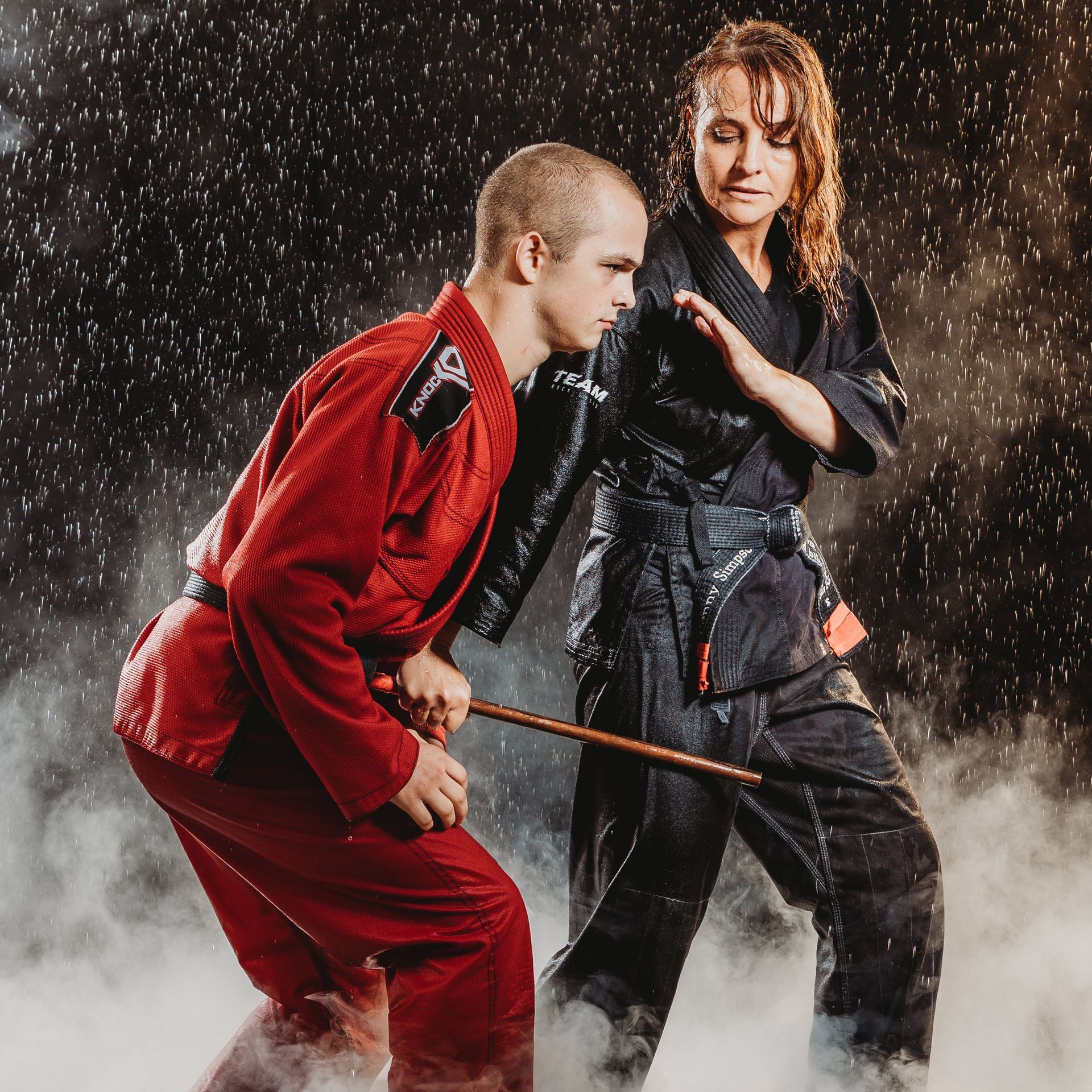 A man and a woman are practicing martial arts in the rain