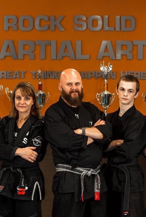 A group of people standing in front of a sign that says rock solid martial art
