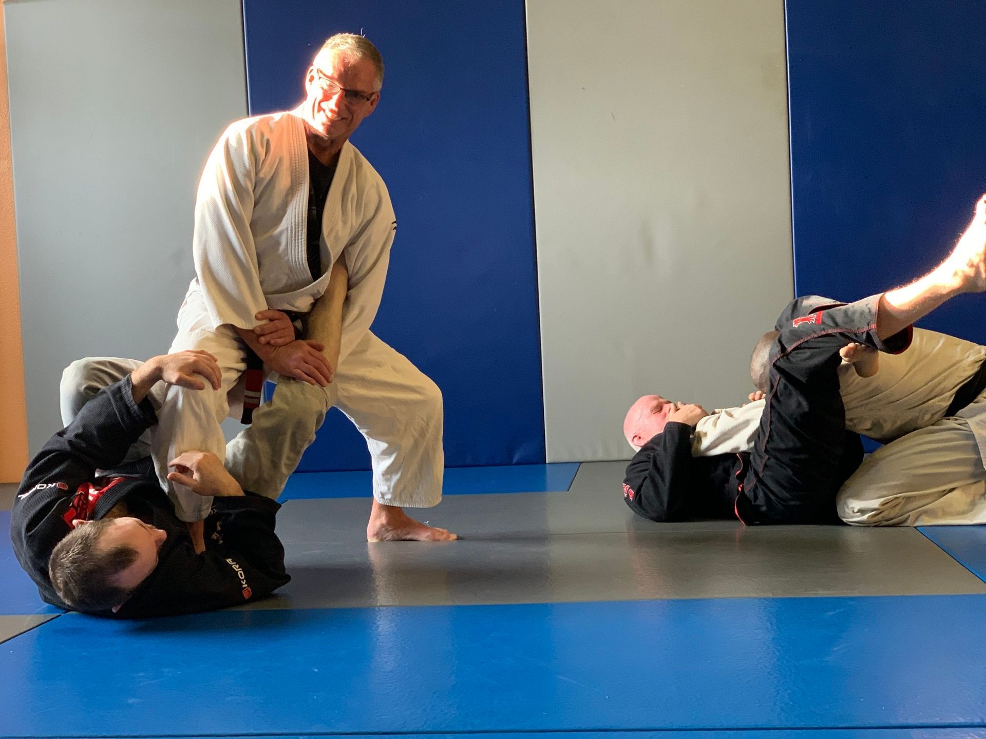 A group of men are practicing martial arts on a blue mat.