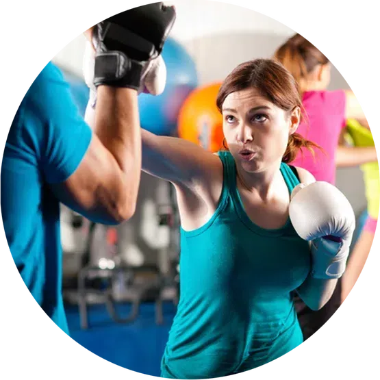 A woman is boxing with a man in a gym