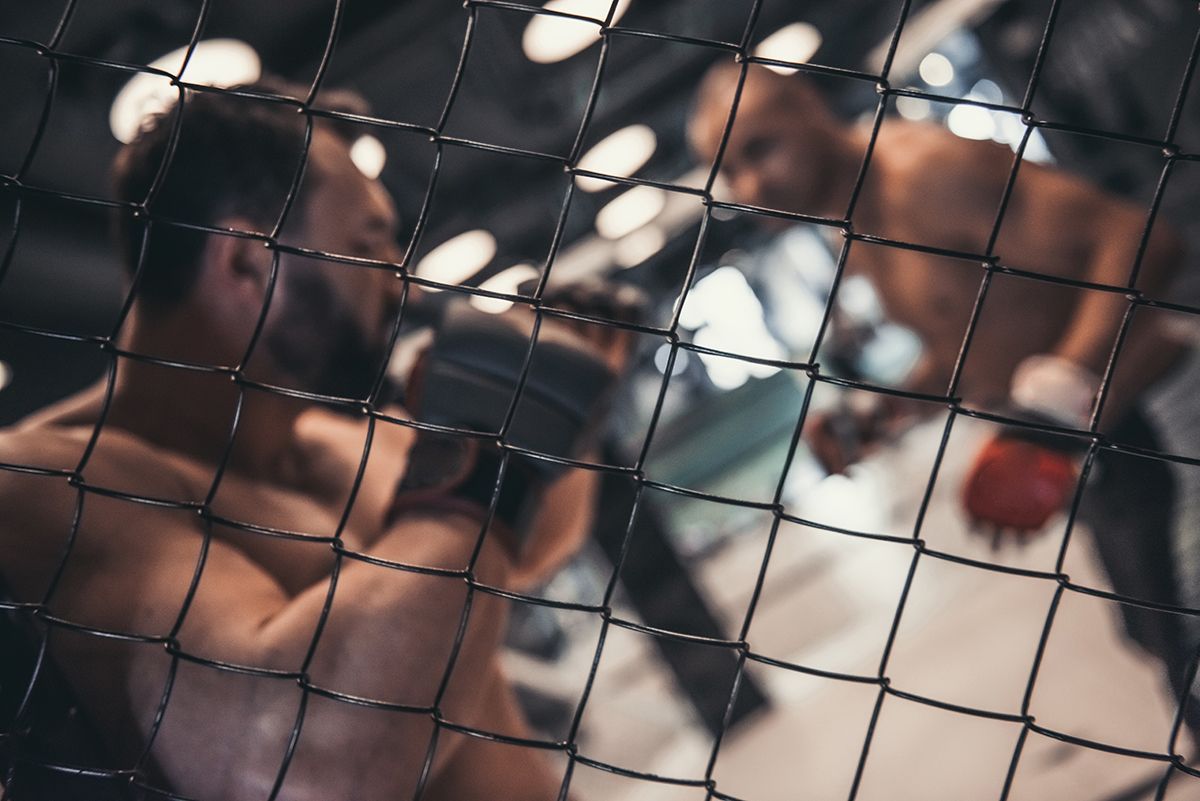 a man in boxing gloves is behind a fence