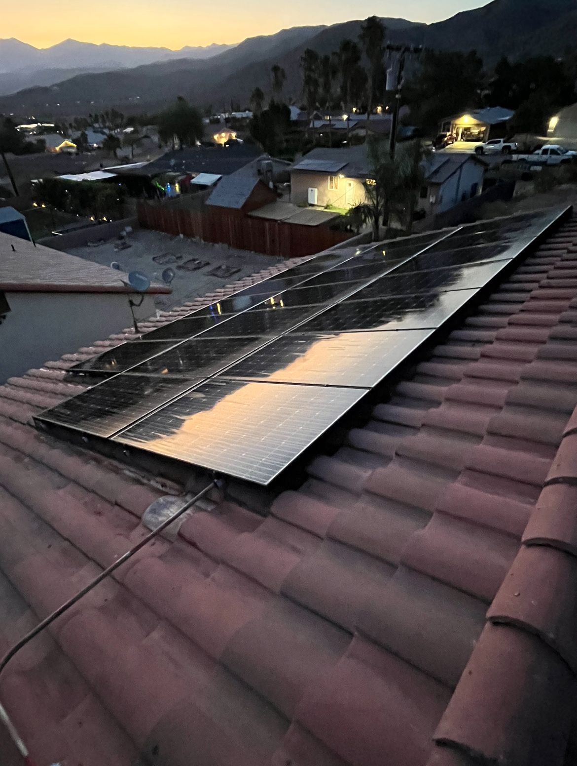 A row of solar panels are sitting on top of a tiled roof.