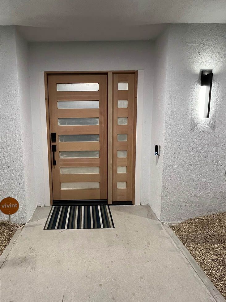A wooden door with a black and white rug in front of it.