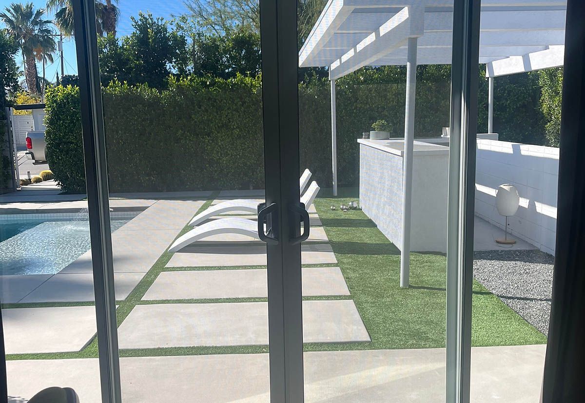 A view of a swimming pool through a sliding glass door.