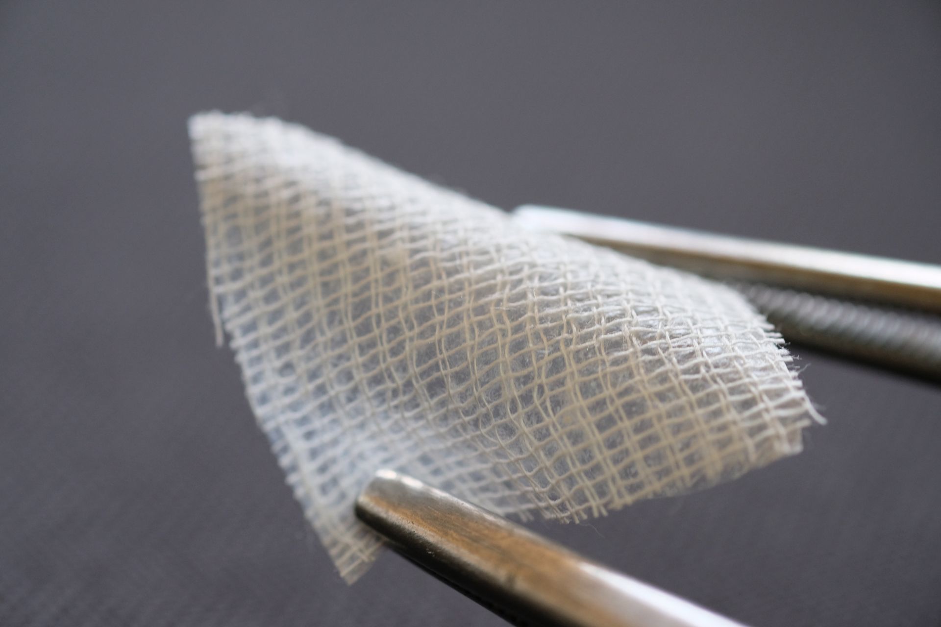 A pair of tweezers holding a piece of gauze