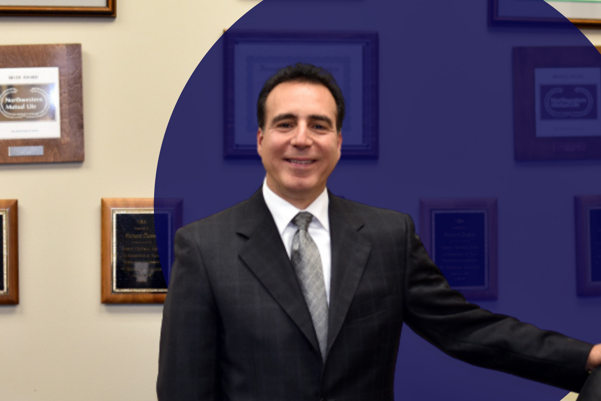 A man in a suit and tie is standing in front of a wall with plaques on it