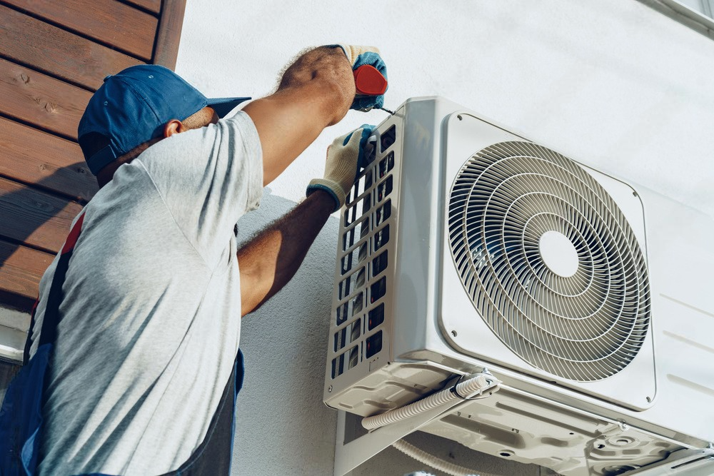 a man is fixing an air conditioner on the side of a building .