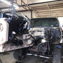 A truck with the engine removed is sitting in a garage.