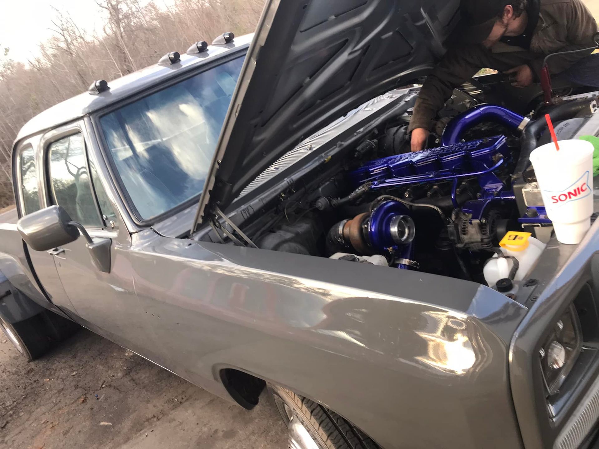 A man is working on the engine of a truck with the hood open.