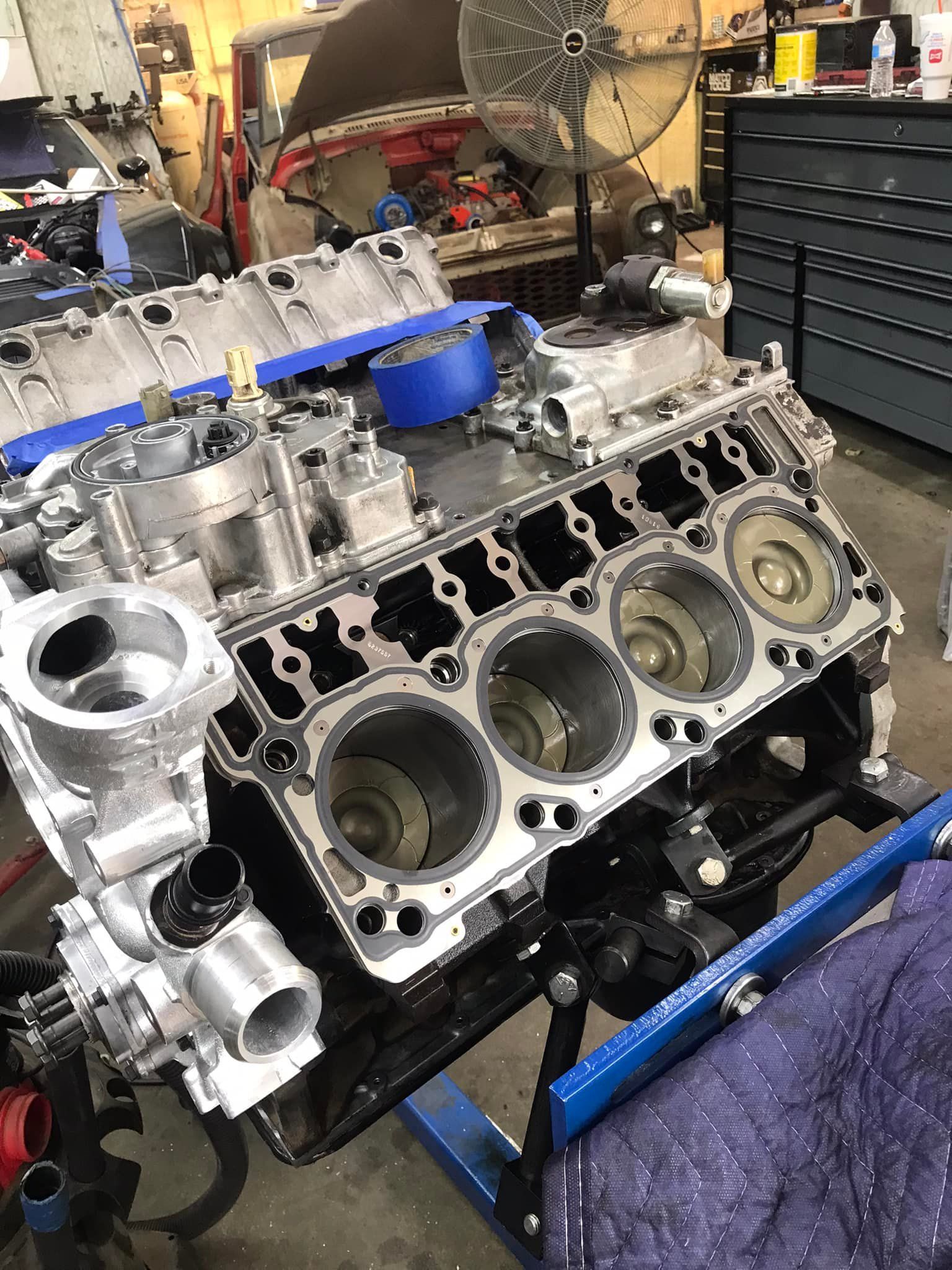 A large engine block is sitting on top of a table in a garage.