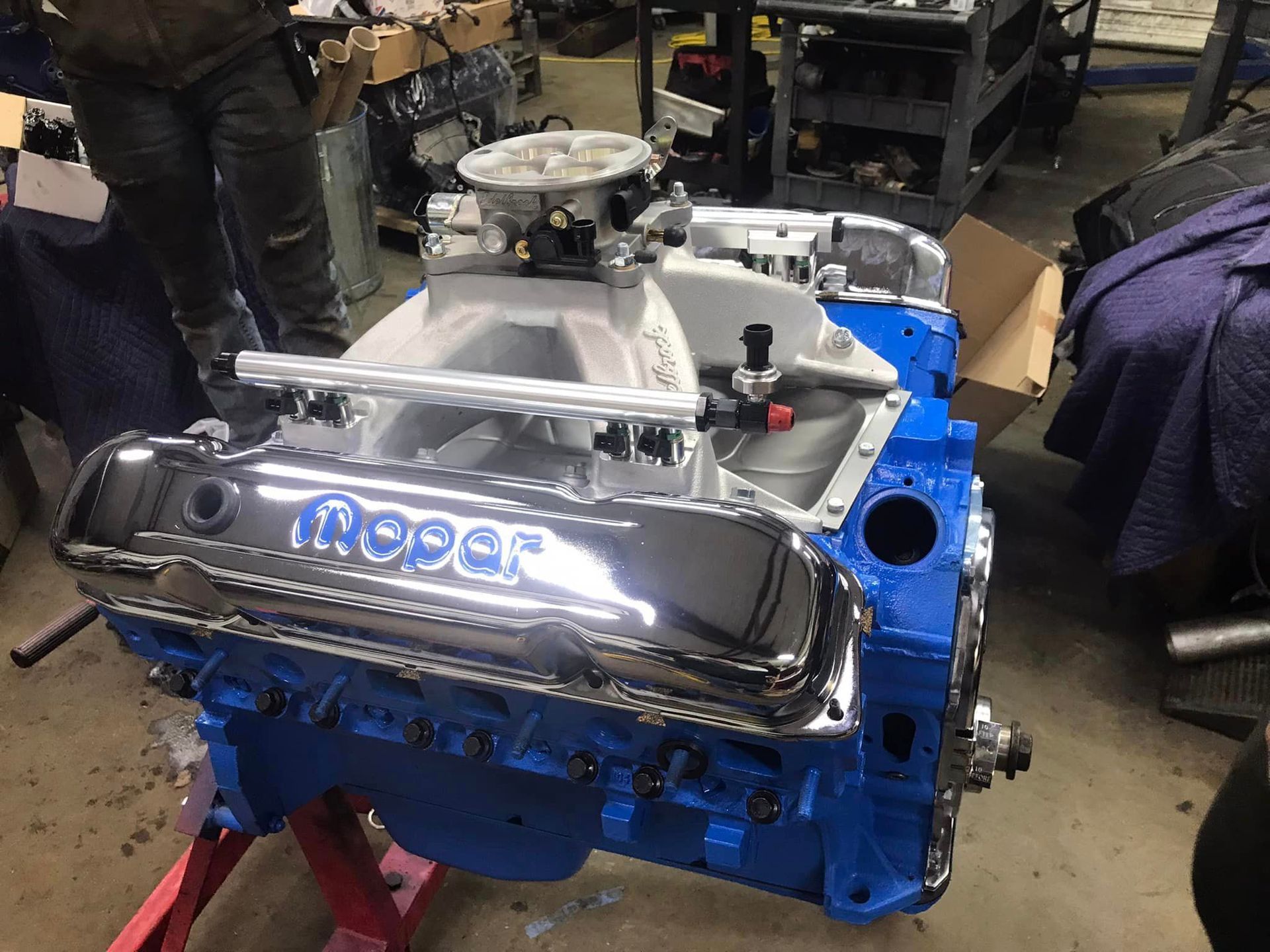 A blue dodge engine is sitting on a red stand in a garage.