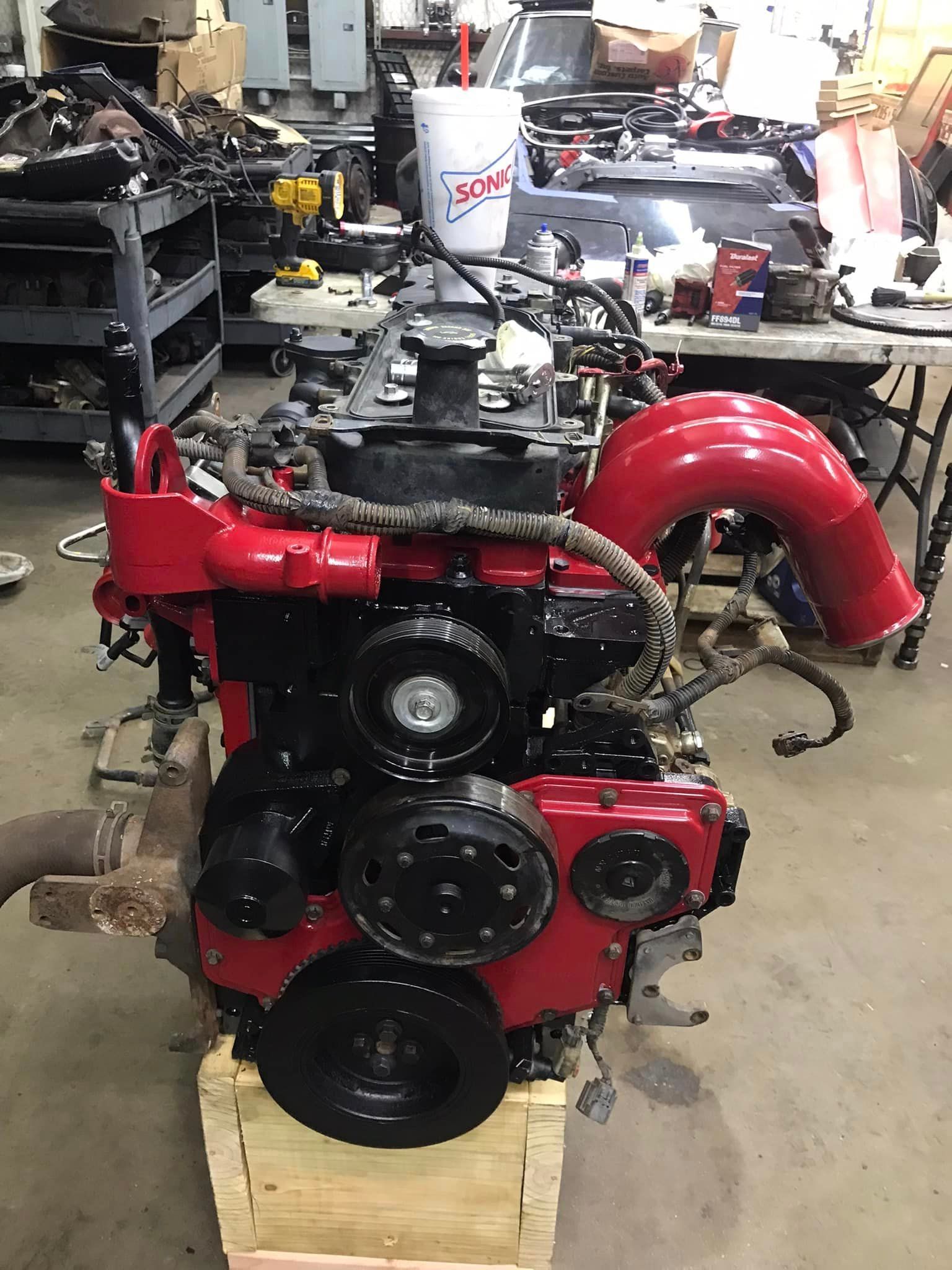 A red engine is sitting on top of a wooden box in a garage.