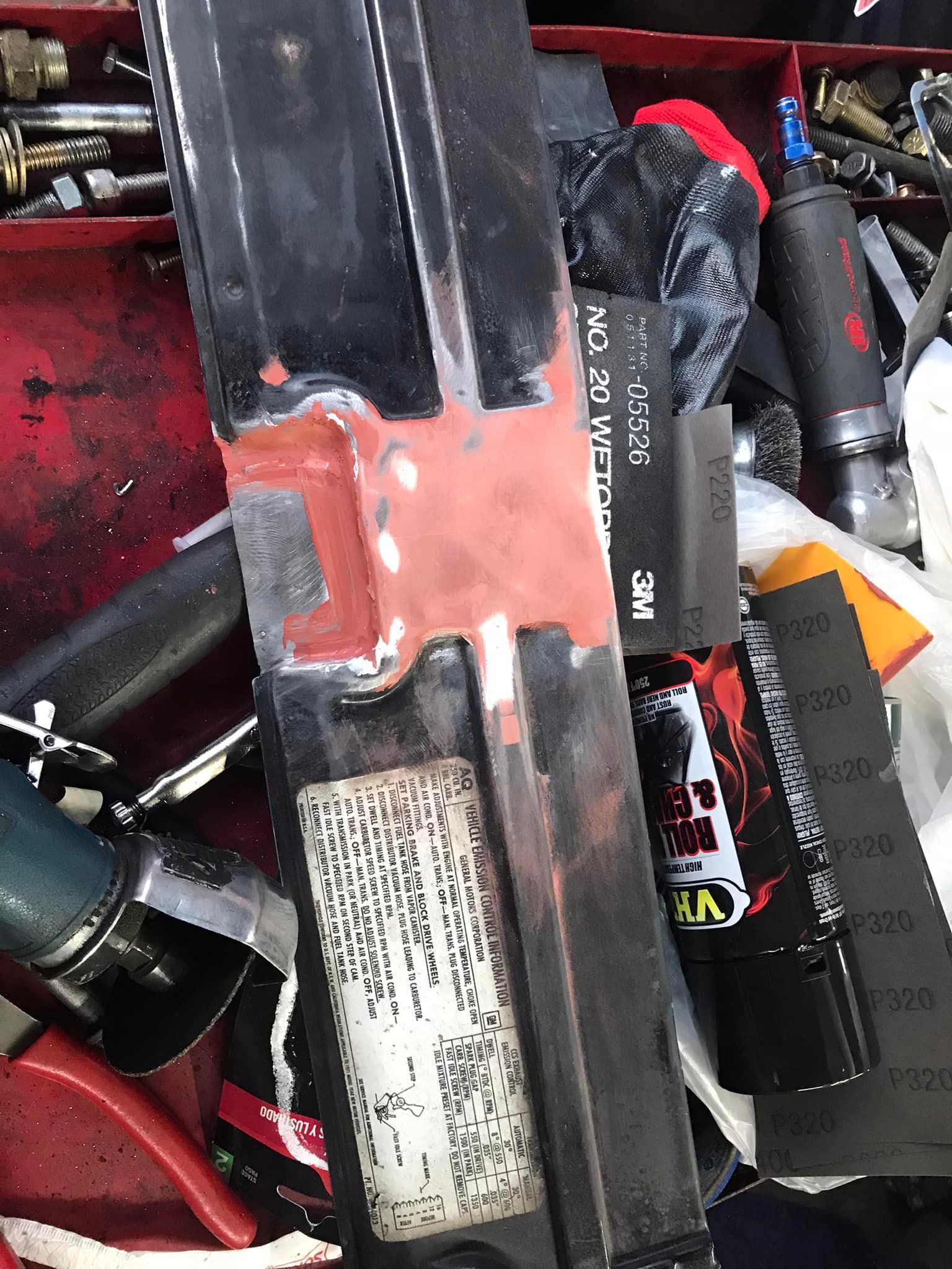 A piece of metal is sitting on top of a pile of tools.