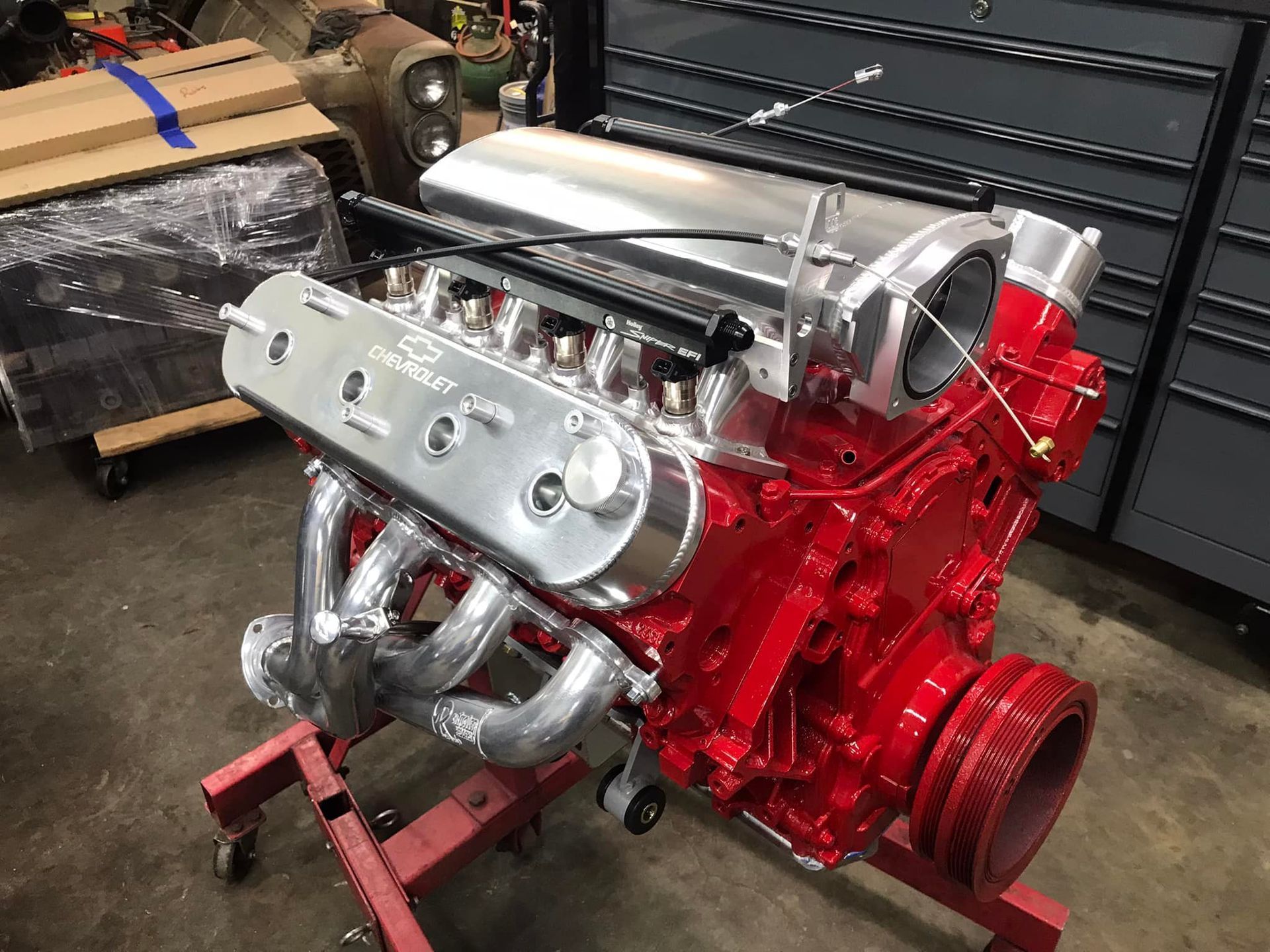 A red engine is sitting on a red stand in a garage.