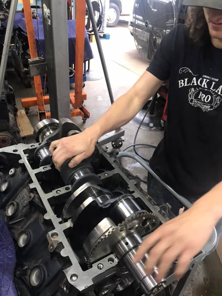 A man in a black shirt is working on a car engine