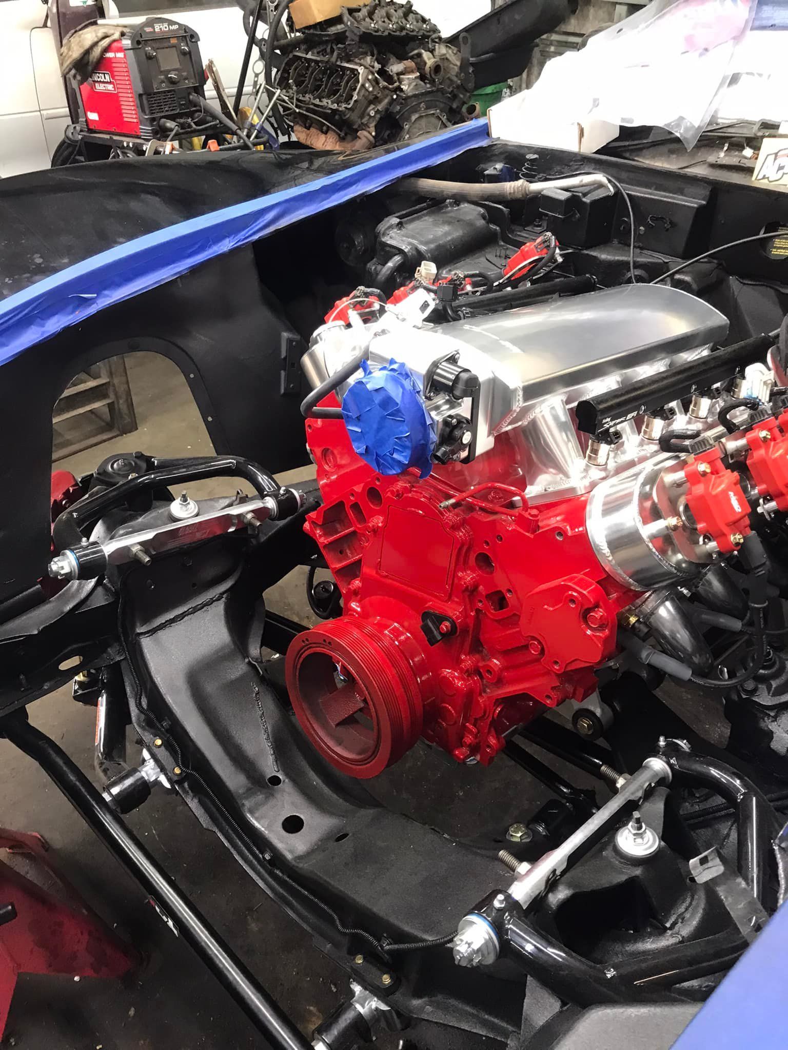 A red engine is sitting inside of a blue car.